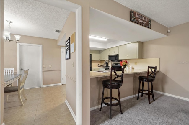 kitchen with visible vents, light countertops, stainless steel microwave, hanging light fixtures, and a peninsula