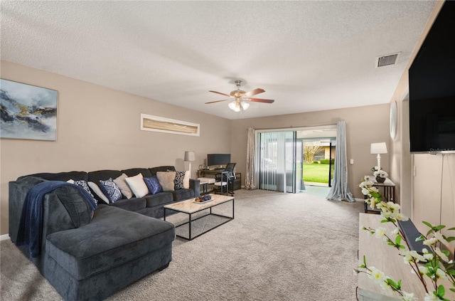 living area featuring a ceiling fan, a textured ceiling, visible vents, and carpet flooring