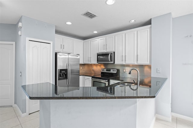 kitchen with light tile patterned flooring, stainless steel appliances, a sink, visible vents, and dark stone counters