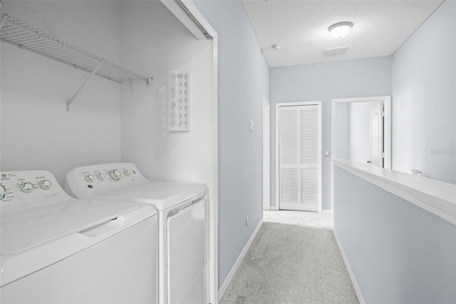 washroom with a textured ceiling, carpet floors, visible vents, baseboards, and washing machine and clothes dryer