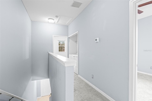 hallway with light colored carpet, visible vents, baseboards, an upstairs landing, and attic access
