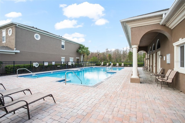 pool with a patio area and fence