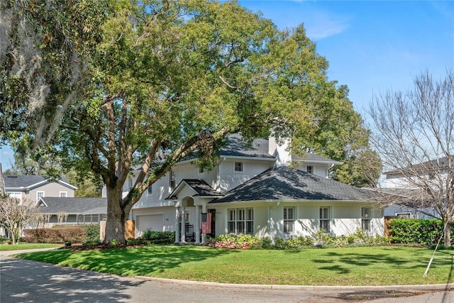 traditional-style home featuring a front lawn, an attached garage, and stucco siding