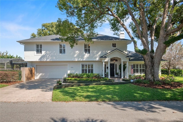 view of front facade with a garage, concrete driveway, a chimney, a front lawn, and stucco siding