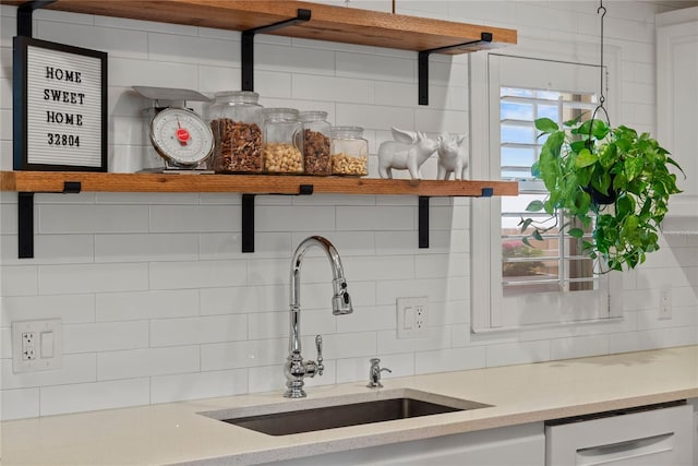 kitchen with a sink, white cabinetry, backsplash, dishwasher, and open shelves