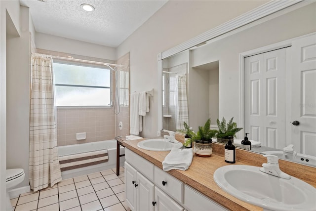 bathroom featuring toilet, a textured ceiling, a sink, and tile patterned floors