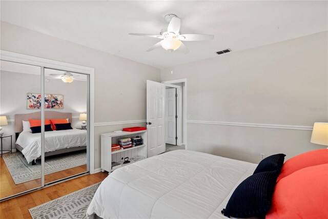 bedroom featuring ceiling fan, a closet, wood finished floors, and visible vents