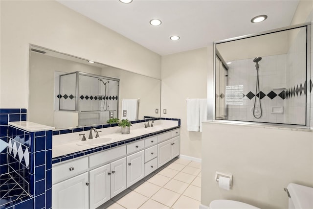 full bath with a sink, a shower stall, toilet, and tile patterned floors