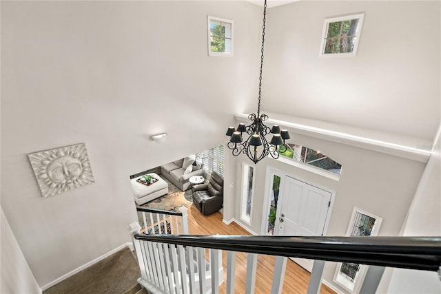 staircase featuring wood finished floors, baseboards, and an inviting chandelier