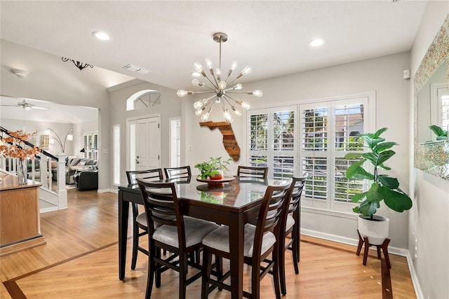 dining room with a healthy amount of sunlight, light wood finished floors, stairs, and visible vents