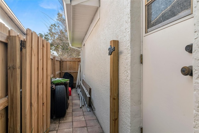 view of side of home featuring fence and stucco siding