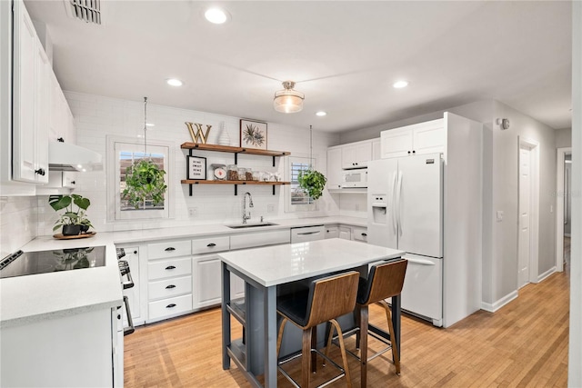 kitchen with white appliances, visible vents, light countertops, under cabinet range hood, and a sink