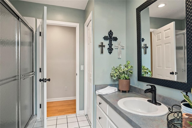 full bathroom featuring a stall shower, tile patterned flooring, vanity, and baseboards