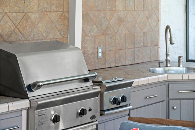 interior details featuring backsplash, gray cabinets, and a sink