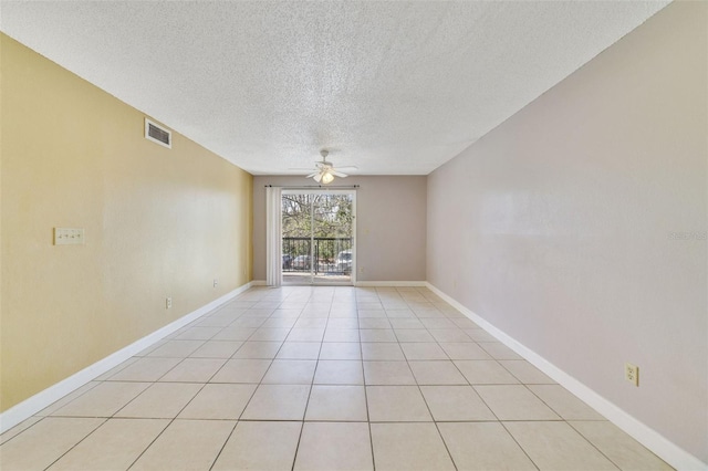 empty room featuring ceiling fan, light tile patterned flooring, and a textured ceiling