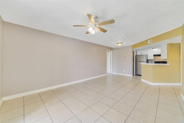 tiled empty room featuring ceiling fan and a textured ceiling