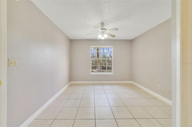 empty room with ceiling fan, light tile patterned floors, and a textured ceiling