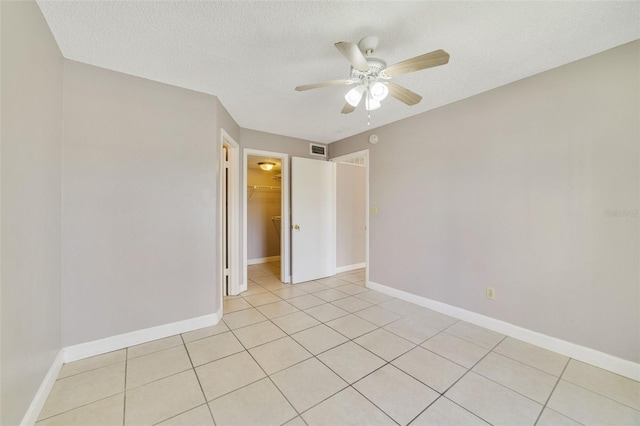 tiled spare room with ceiling fan and a textured ceiling