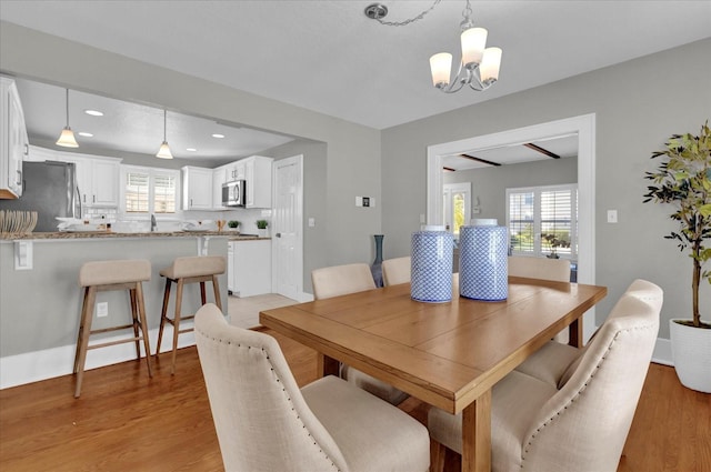 dining space featuring a healthy amount of sunlight, a chandelier, and light wood-type flooring