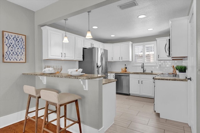 kitchen with kitchen peninsula, stainless steel appliances, and white cabinets