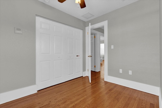 unfurnished bedroom with hardwood / wood-style floors, a closet, and ceiling fan