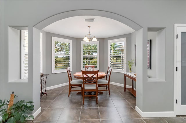 dining area with a notable chandelier and dark tile patterned flooring