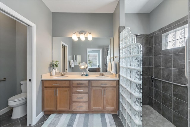 bathroom featuring toilet, vanity, tile patterned flooring, and a tile shower