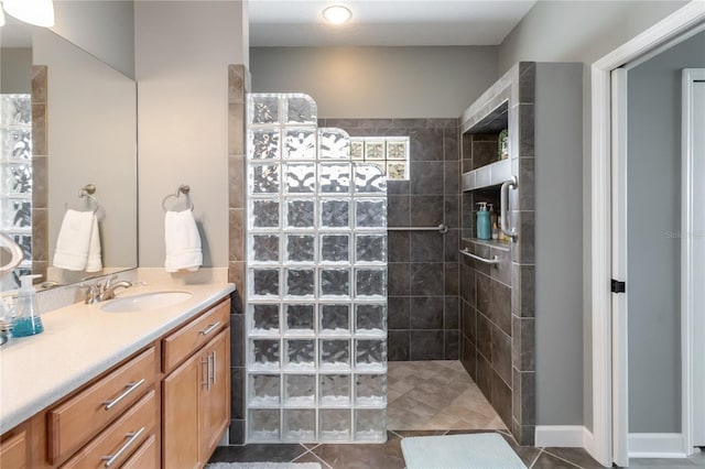 bathroom with tile patterned flooring, vanity, and a tile shower