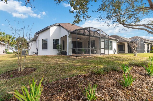 back of house with glass enclosure, cooling unit, and a lawn