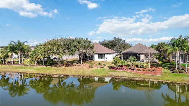 back of property featuring a lawn, a water view, and a lanai