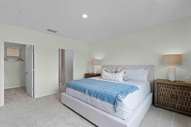 bedroom featuring light carpet, a walk in closet, and a closet