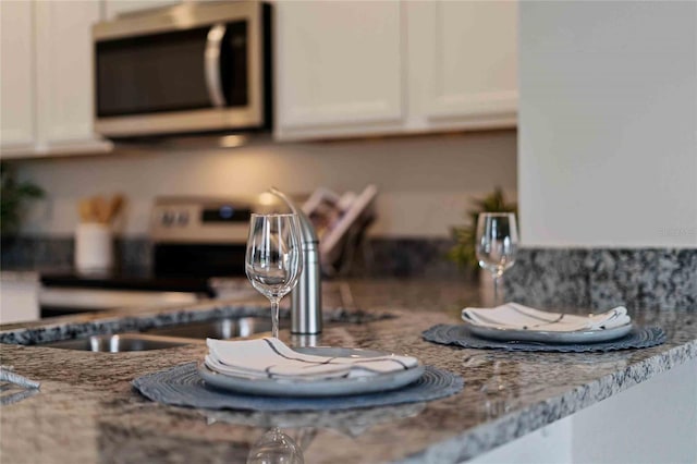 details featuring white cabinets and light stone counters