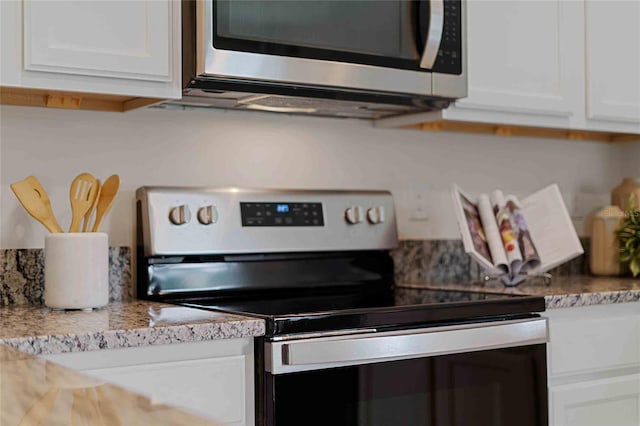 kitchen featuring white cabinets, appliances with stainless steel finishes, and light stone counters