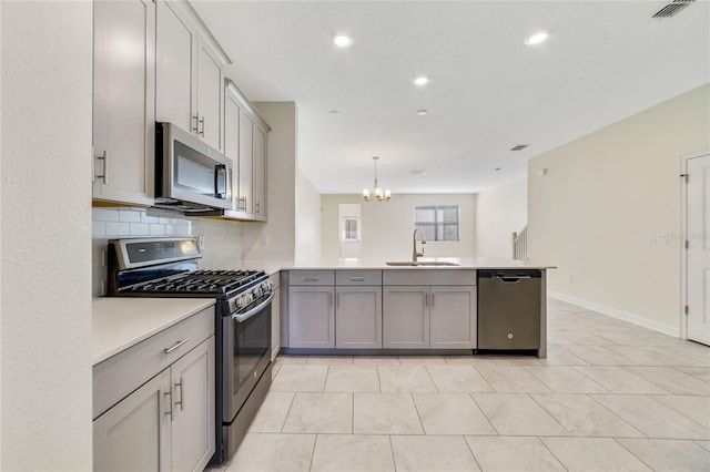 15088 Night Heron Dr, Winter Garden, FL 34787 - kitchen with appliances with stainless steel finishes, a peninsula, gray cabinetry, a chandelier, and tasteful backsplash