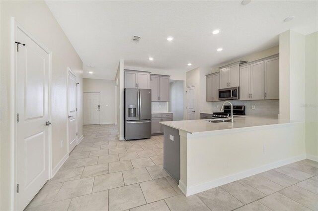 15088 Night Heron Dr, Winter Garden, FL 34787 - kitchen featuring stainless steel appliances, gray cabinets, a peninsula, light countertops, and backsplash