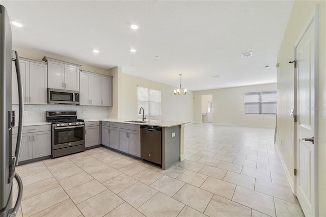 15088 Night Heron Dr, Winter Garden, FL 34787 - kitchen featuring appliances with stainless steel finishes, gray cabinets, a chandelier, backsplash, and open floor plan
