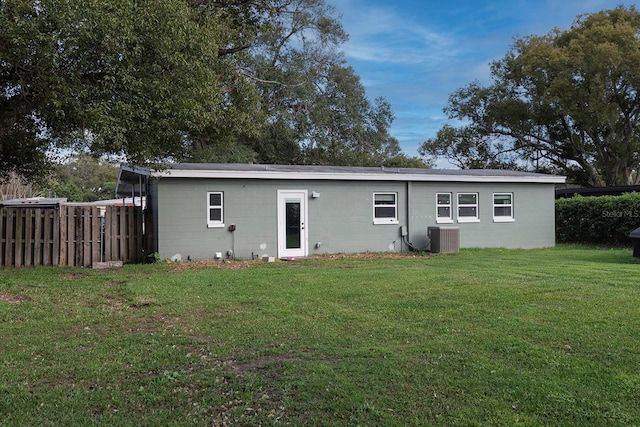 rear view of property with cooling unit and a lawn