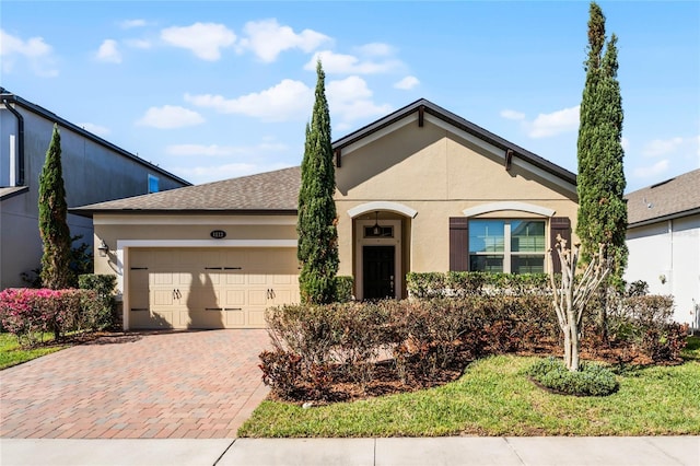 view of front of property with a shingled roof, decorative driveway, an attached garage, and stucco siding