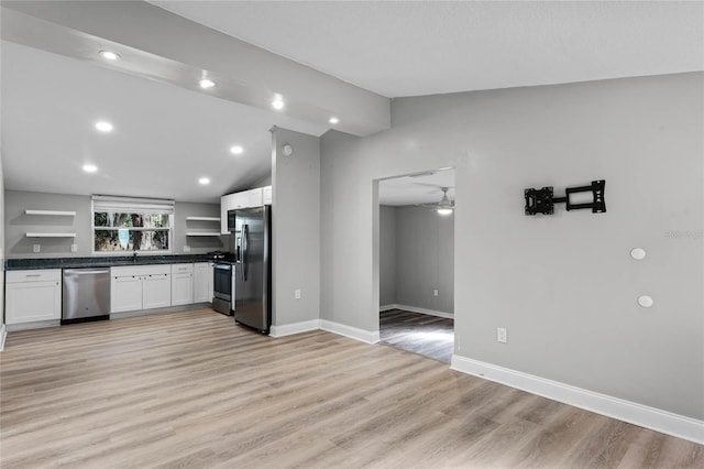 kitchen with appliances with stainless steel finishes, white cabinets, vaulted ceiling, and light hardwood / wood-style floors