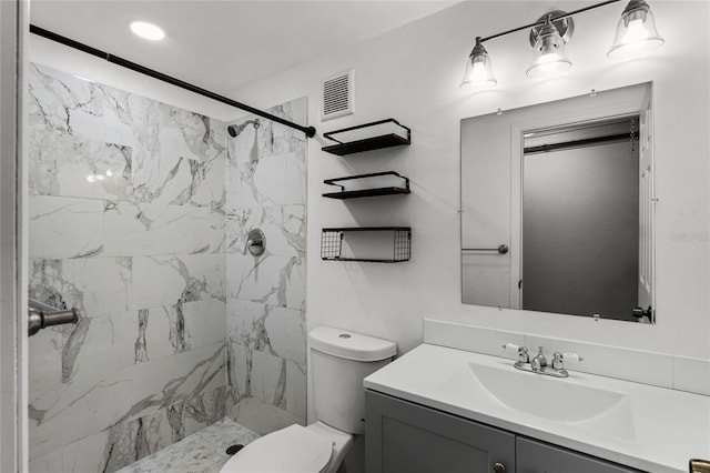 bathroom featuring toilet, vanity, and tiled shower