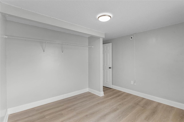 unfurnished bedroom featuring a textured ceiling, a closet, and light hardwood / wood-style floors