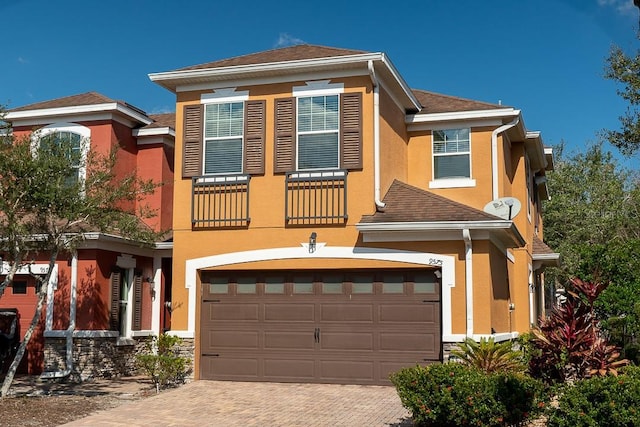 view of front facade with a garage, decorative driveway, a balcony, and stucco siding