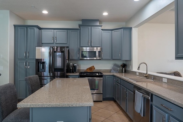 kitchen with a kitchen island, light stone counters, stainless steel appliances, a sink, and light tile patterned flooring