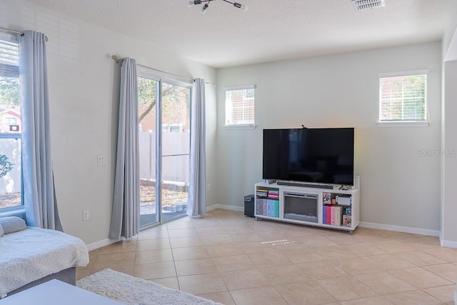 living room with a healthy amount of sunlight, visible vents, a textured ceiling, and light tile patterned flooring