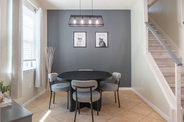 dining area with light tile patterned floors, stairs, and baseboards