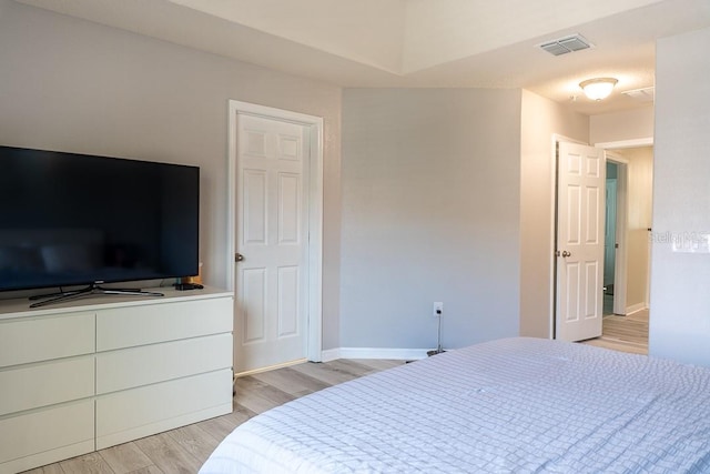 bedroom with baseboards, visible vents, and light wood finished floors