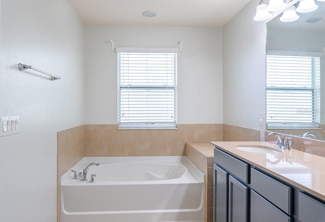 full bath with plenty of natural light, a bath, and vanity