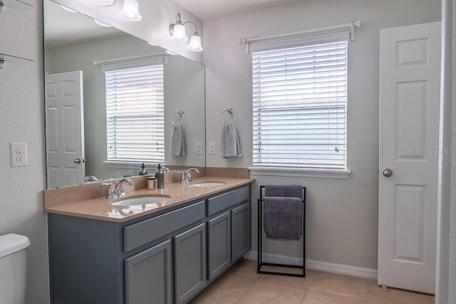 bathroom with tile patterned flooring, a healthy amount of sunlight, and a sink