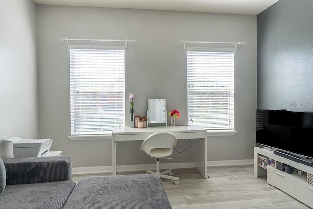 office with light wood-type flooring, a healthy amount of sunlight, and baseboards