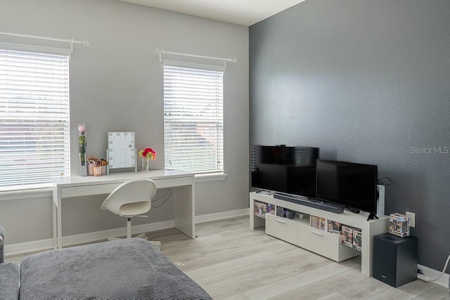 office space with light wood-type flooring, built in desk, and baseboards